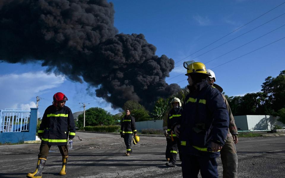Firefighters are seen near an oil tank on fire in Matanzas, Cuba - YAMIL LAGE 