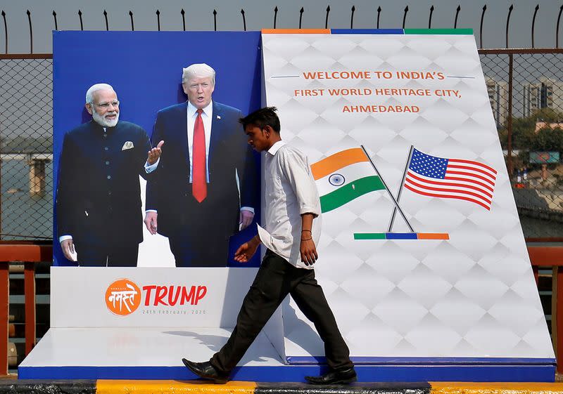 A man crosses a bridge past a hoarding, ahead of U.S. President Trump's visit, in Ahmedabad