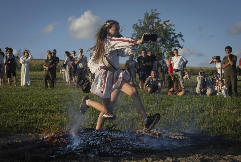 A young woman takes selfie as she jumps over the fire at a traditional Midsummer Night celebration near capital Kyiv, Ukraine, Sunday, June 23, 2024. The age-old pagan festival is still celebrated in Ukraine amid the third year of Russia-Ukraine war. Many people believe that jumping over the fire will cleanse them of evil spirits.(AP Photo/Efrem Lukatsky)