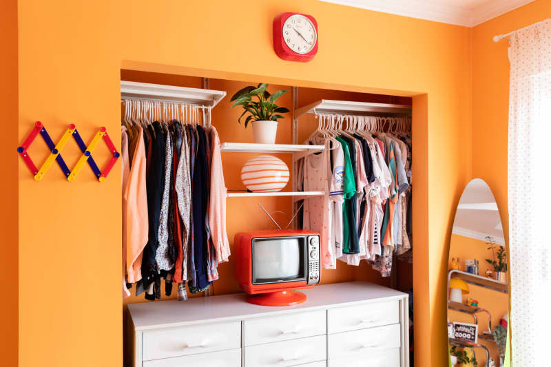 Orange painted wall in bedroom with vintage television on nightstand.