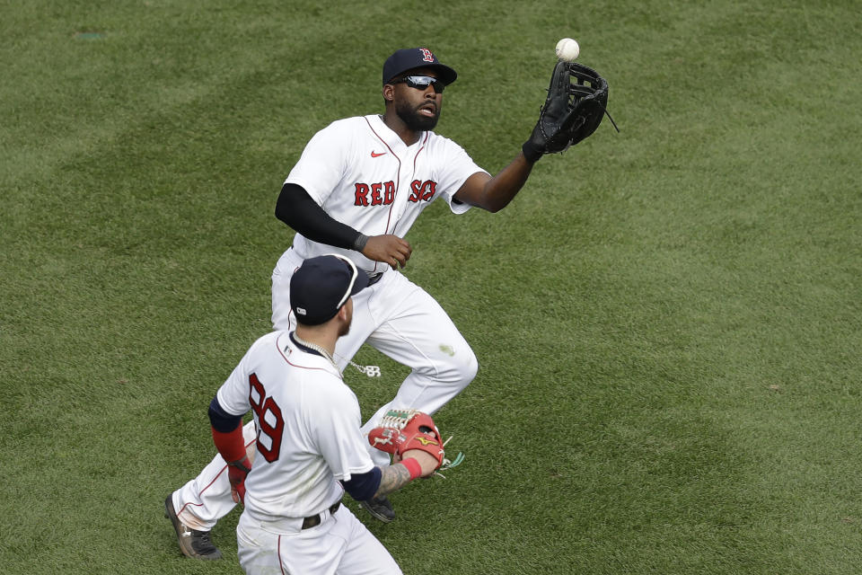 Boston Red Sox's Jackie Bradley Jr., top, gets his glove on an RBI-single by Baltimore Orioles' Chris Davis after the ball bounced off the Green Monster wall as Alex Verdugo, bottom, runs beside him during the ninth inning of a baseball game, Sunday, July 26, 2020, in Boston. (AP Photo/Steven Senne)