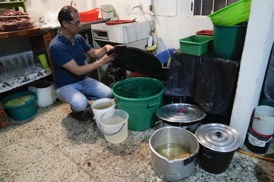 Restaurant owner Luis Alirio Soler shows buckets of water while his kitchen continues to operate during a 24-hour water restriction in Bogota, Colombia, Friday, April 12, 2024. Water rationing in the capital began on Thursday due to the low level of water in reservoirs that give drinking water to the capital, a consequence of the El Niño weather phenomenon. (AP Photo/Fernando Vergara)