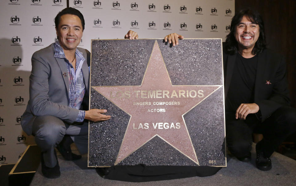 ARCHIVO - Los Temerarios, Gustavo y Adolfo Ángel, de izquierda a derecha, posan con su estrella al incorporarse al Paseo de las Estrellas de Las Vegas el 13 de septiembre del 2012. Los temerarios anunciaron su separación el lunes 28 de agosto de 2023. La banda grupera mexicana señaló que realizará una última gira internacional que concluirá en 2024. (Foto AP/Julie Jacobson)