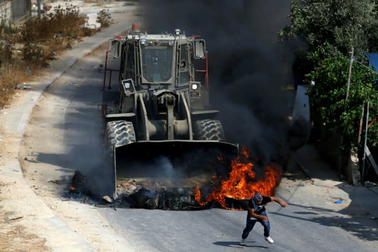 A Palestinian youth runs from the path of an Israeli army bulldozer during clashes in the village of Kobar, west of Ramallah, on July 22, 2017