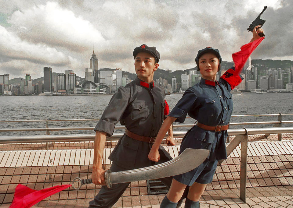 FILE - In this Tuesday, July 21, 1998, file photo, dancers of China's National Ballet, Sun Jie, left, and Zou Zhi Rui, dressed in military uniforms pose for photographers at Hong Kong's waterfront. A year after Beijing imposed a harsh national security law on Hong Kong, the civil liberties that raised hopes for more democracy are fading. (AP Photo/Vincent Yu, File)