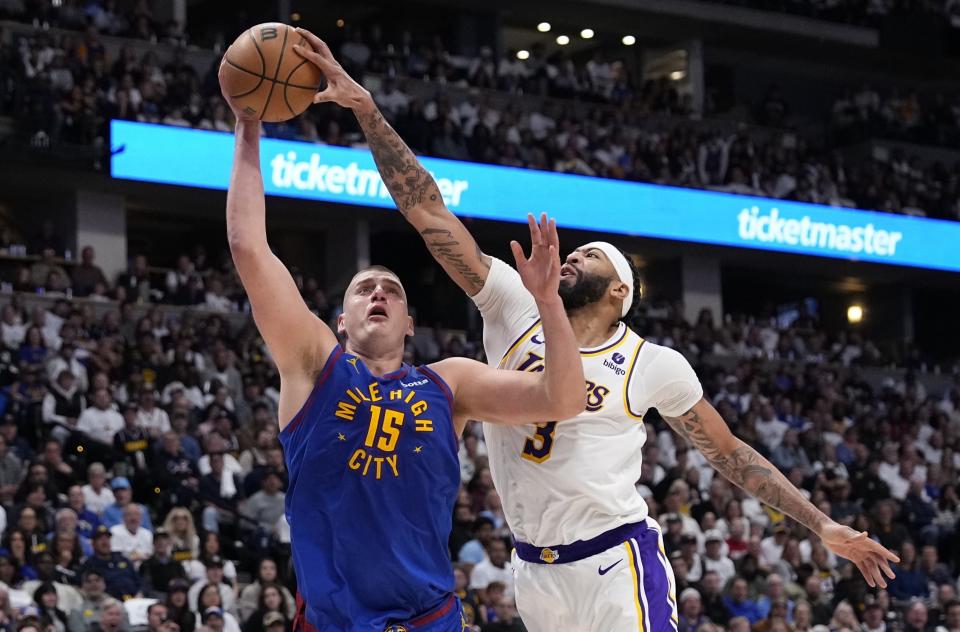 Los Angeles Lakers forward Anthony Davis (3) gets a hand on the ball against Denver Nuggets center Nikola Jokic (15) during the second half in Game 1 of an NBA basketball first-round playoff series Saturday, April 20, 2024, in Denver. (AP Photo/Jack Dempsey)