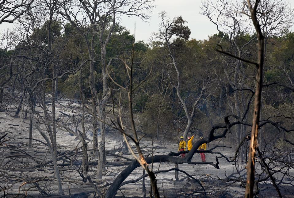 Firefighters work Wednesday amid some of the destruction caused by the Parmer Lane Fire.