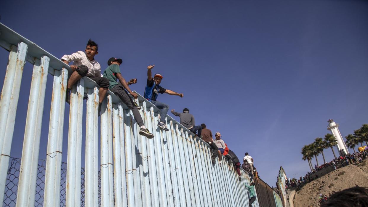 Migranten aus Mittelamerika sitzen in Tijuana auf dem Grenzzaun zwischen Mexiko und den USA. Foto: Eduardo Jaramillo/NOTIMEX