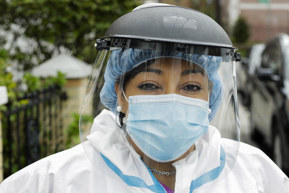 In this Thursday, April 30, 2020, photo, Linda Silva, a nurse's assistant, poses for a portrait in the Queens borough of New York. Silva, who tested positive for COVID-19, returned to work after recovering. It’s been more than a month since she has hugged her two sons or her husband. (AP Photo/Frank Franklin II)