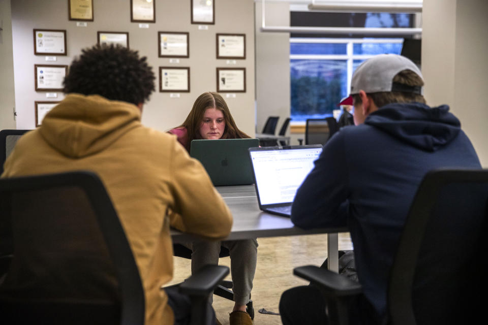 Sports Editor Kenna Roering works with sports reporters in The Daily Iowan newsroom, Feb. 29, 2024, in Iowa City, Iowa. With many small town newspapers closing, student journalists across the country are heading to school board meetings and covering local elections to fill the void. But now an effort at the University of Iowa has taken it one step further, with the student paper buying two struggling weeklies in what is believed to be a first. (Emily Nyberg/The Daily Iowan via AP)