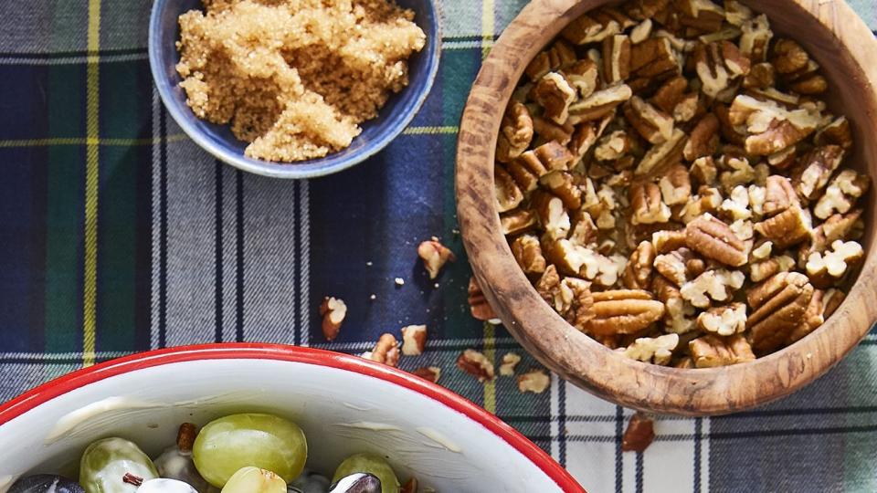 grape salad in a bowl with pecans and brown sugar in smaller bowls near by