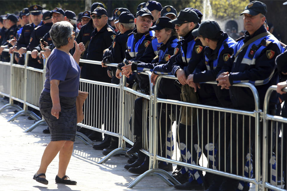 Police officers stand guard as a woman gestures during an anti-government rally in Tirana, Albania, Thursday, March 21, 2019. Thousand opposition protesters have gathered in front of Albania's parliament building calling for the government's resignation and an early election. Rally is part of the center-right Democratic Party-led opposition's protests over the last month accusing the leftist Socialist Party government of Prime Minister Edi Rama of being corrupt and linked to organized crime. (AP Photo/Hektor Pustina)