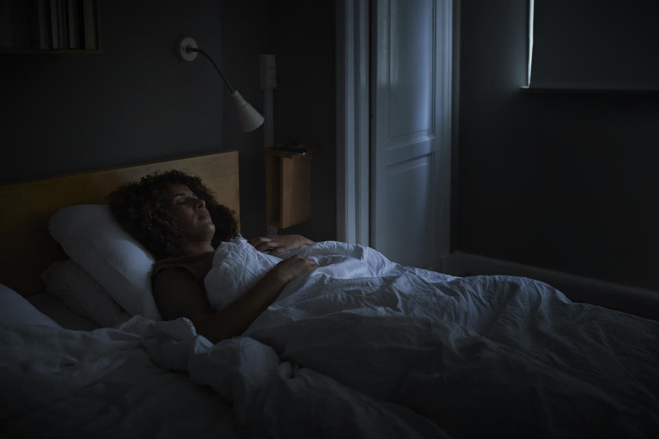 Middle aged woman sleeping on a bed at home in the dark.