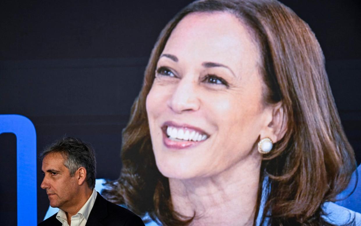 Michael Cohen, former attorney for Donald Trump, stands  in front of a sign with a picture of Kamala Harris