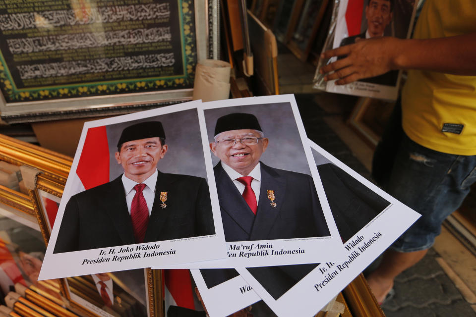 In this Wednesday. Oct. 16, 2019, photo, portraits of Indonesian President Joko Widodo, left, and Vice President-elect Ma'ruf Amin are displayed at a stall in Jakarta, Indonesia. Known for his down-to-earth style with a reputation for clean governance, Widodo's signature policy has been improving Indonesia's inadequate infrastructure and reducing poverty, which afflicts close to a tenth of Indonesia's nearly 270 million people. But raising money would be harder at a time of global economic slowdown, major trade conflicts and falling exports. (AP Photo/Tatan Syuflana)