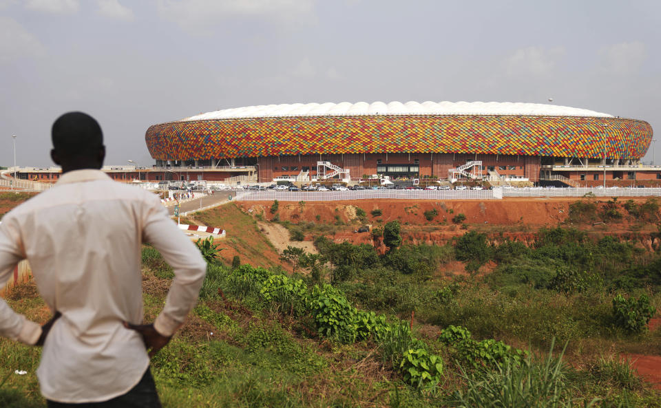 A man standing outside a newly build Olembe stadium in Yaoundé at, Cameroon, Saturday, Jan. 8, 2022. The African Cup of Nations takes place in Cameroon and starts on Sunday, Jan. 9. (AP Photo/Themba Hadebe)