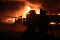 In this photo provided Saturday, March 6, 2021 by the Syrian Civil Defense group known as the White Helmets, Civil Defense workers extinguish burning oil tanker trucks after a suspected missile strike around the towns of Jarablus and al-Bab, near the border with Turkey, in western Aleppo province, Syria. Syrian opposition groups and the Syrian Observatory for Human Rights, based in Britain, blamed Russia for the Friday night strikes. (Syrian Civil Defense White Helmets via AP)