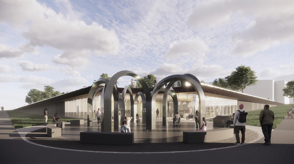 A rendering by Jin Young Song and Douglass Alligood of the planned Buffalo supermarket shooting memorial shows interconnected stone pillars and arches, and a windowed building where exhibitions and events will be held in Buffalo, N.Y. New York state has committed $5 million to the $15 million project and Buffalo will contribute $1 million to the permanent memorial honoring the 10 Black victims of a racist mass shooting at a Buffalo supermarket in 2022. (Rendering by Jin Young Song and Douglass Alligood via AP)