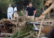 People look at rescue workers searching among collapsed houses following a landslide caused by Typhoon Wipha on Izu Oshima island, south of Tokyo, in this photo taken by Kyodo October 16, 2013. Eight people were killed and over 30 missing, with nearly 20,000 people ordered to evacuate and hundreds of flights cancelled as Typhoon Wipha pummelled the Tokyo region on Wednesday, leaving piles of wreckage on one small island but largely sparing the capital. (REUTERS/Kyodo)