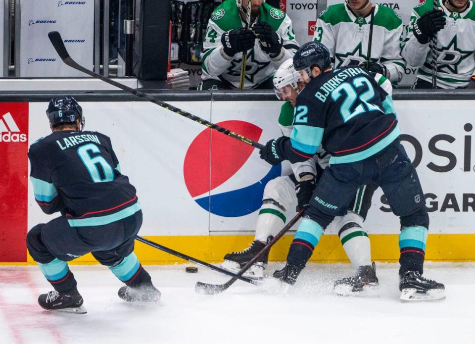 Seattle Kraken right wing Oliver Bjorkstrand (22) and Seattle Kraken defenseman Adam Larsson (6) try to steal the puck from Dallas Stars center Luke Glendening (11) as he’s pinned against the wall during the first period of game four of the second round of the 2023 Stanley Cup Playoffs in Seattle, Wash. on May 9, 2023.