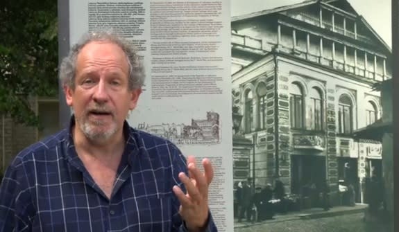 Archaeologist Jon Seligman stands next to a picture of the Great Synagogue of Vilna in Lithuania. Nazi destroyed the synagogue, and now archaeologists are searching for its remains.