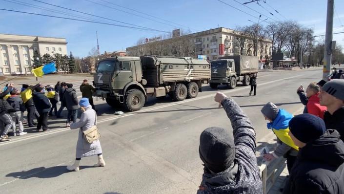 A demonstrator gestures as others, displaying Ukrainian flags, chant &quot;go home&quot; and walk towards Russian military vehicles at a pro-Ukraine rally amid Russia&quot;s invasion, in Kherson, Ukraine March 20, 2022