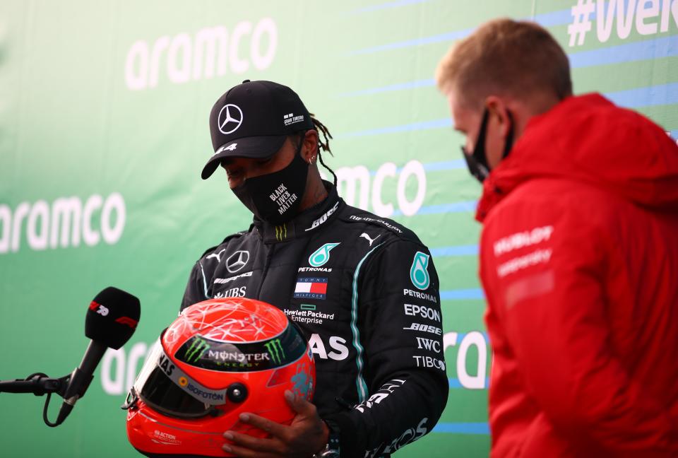 Lewis Hamilton is presented with one of Michael Schumacher’s helmets by his son Mick (Reuters)