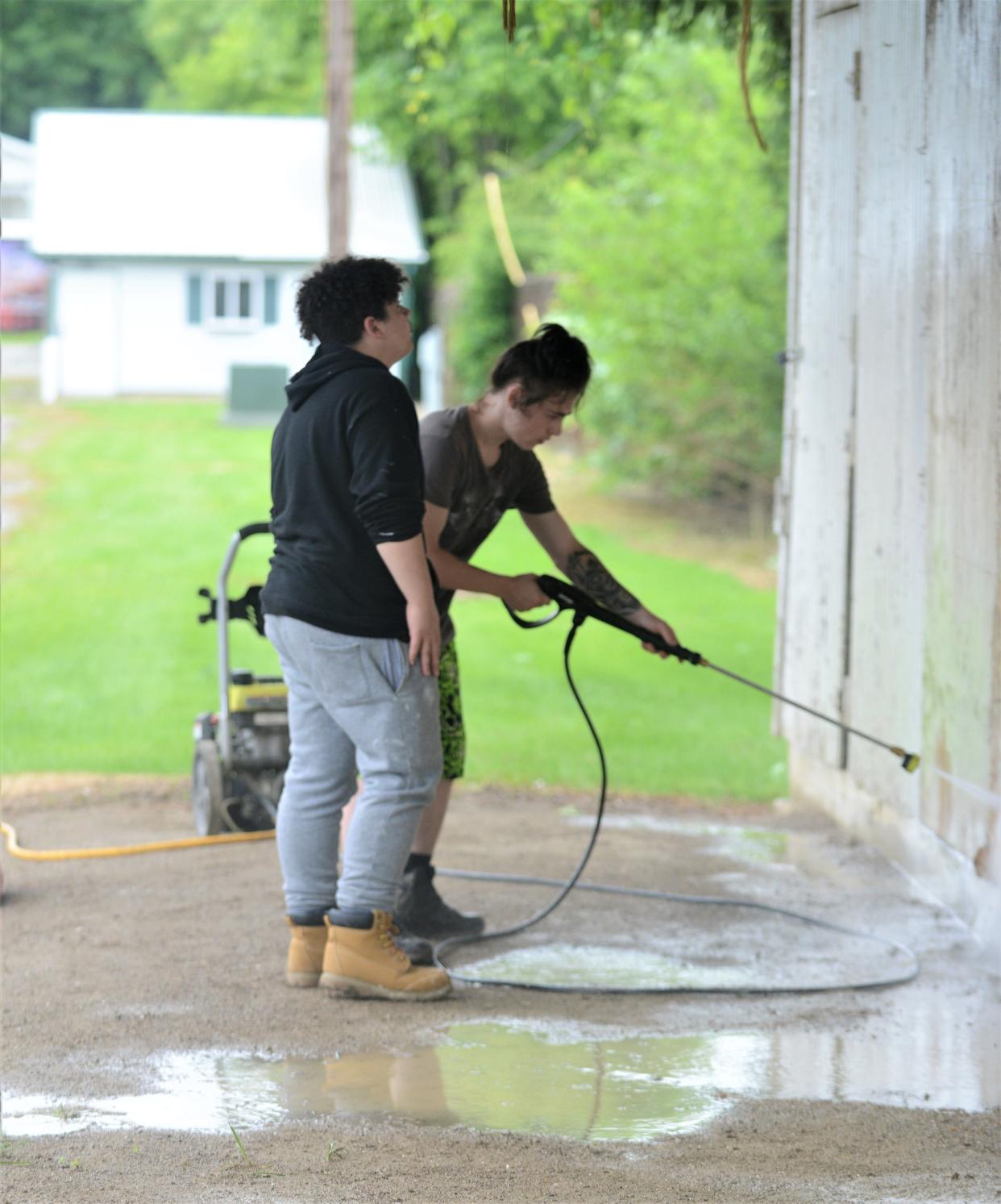 Foxfire High School students, Sean Smith (left) and Shawnte Hanning power wash the horse stables at the Muskingum County Fairgrounds. They are part of a group of students participating in the summer work program.