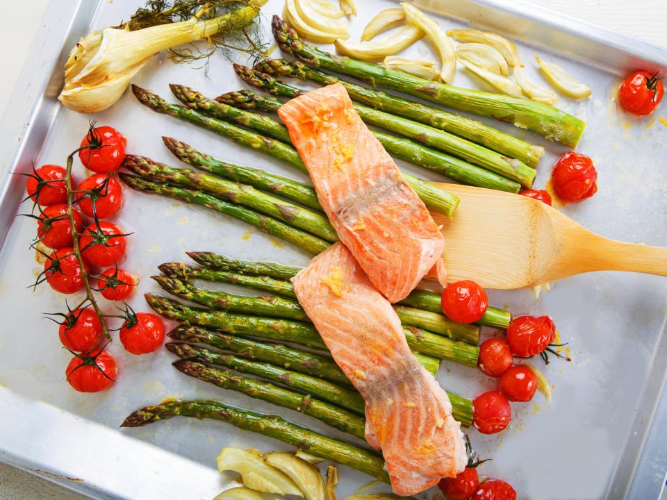 Salmon fish and vegetables: green aspargus, cherry tomatoes and fennel, on oven tray