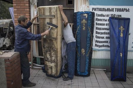 People clean a coffin from an undertaker's showroom that was recently shelled in Donetsk, eastern Ukraine, September 16, 2014. REUTERS/Marko Djurica