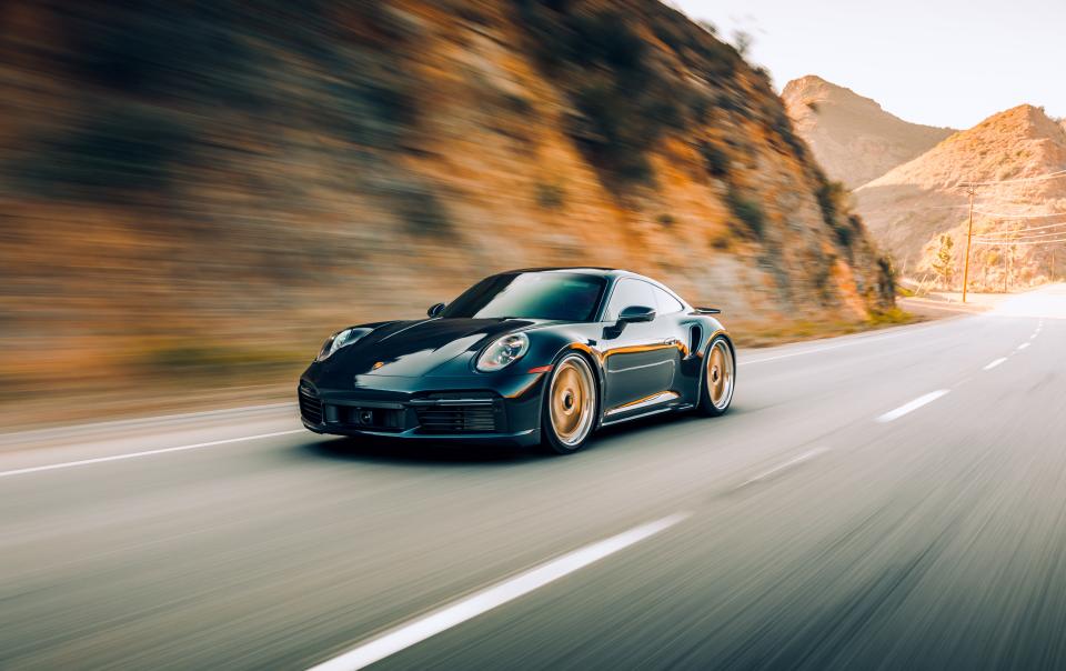 LA, CA, USA
8/12/2022
Porsche 911 Turbo S driving on the road with a rock wall next to the car