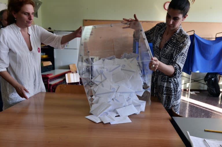 Polling station officials empty a ballot box to count the votes at a polling station in Athens