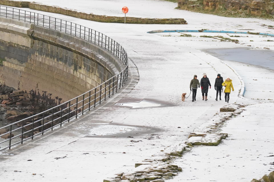 People walk along the seafront at Whitley Bay in Northumberland after a light covering of snow. Snow and ice have swept across parts of the UK, with cold wintry conditions set to continue for days. Picture date: Sunday December 11, 2022.