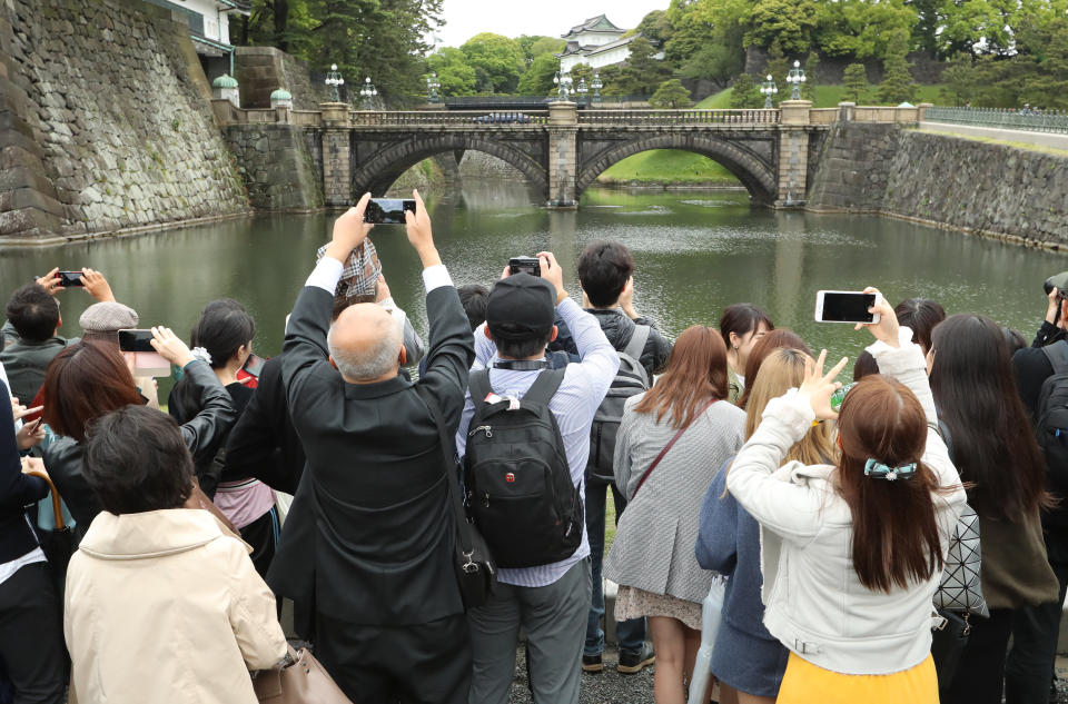 People take photos of the famous double bridge in the compound of Imperial Palace in Tokyo Tuesday, April 30, 2019. Emperor Akihito is set to abdicate later in the day as Japan embraces the end of his reign with an emotion mixed with reminiscence and hopes for a new era. (AP Photo/Eugene Hoshiko)