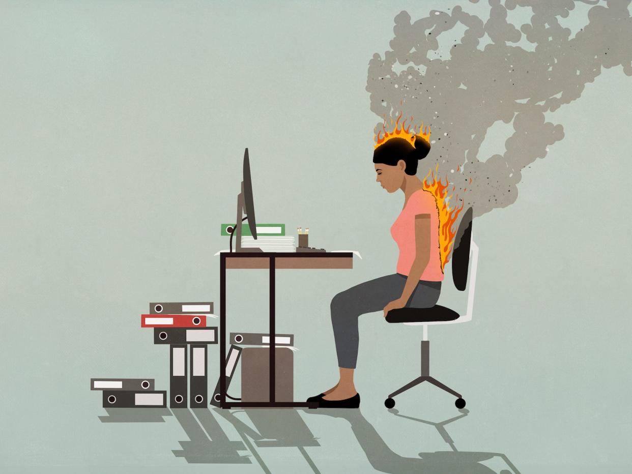 overworked worker sits at a desk facing burnout