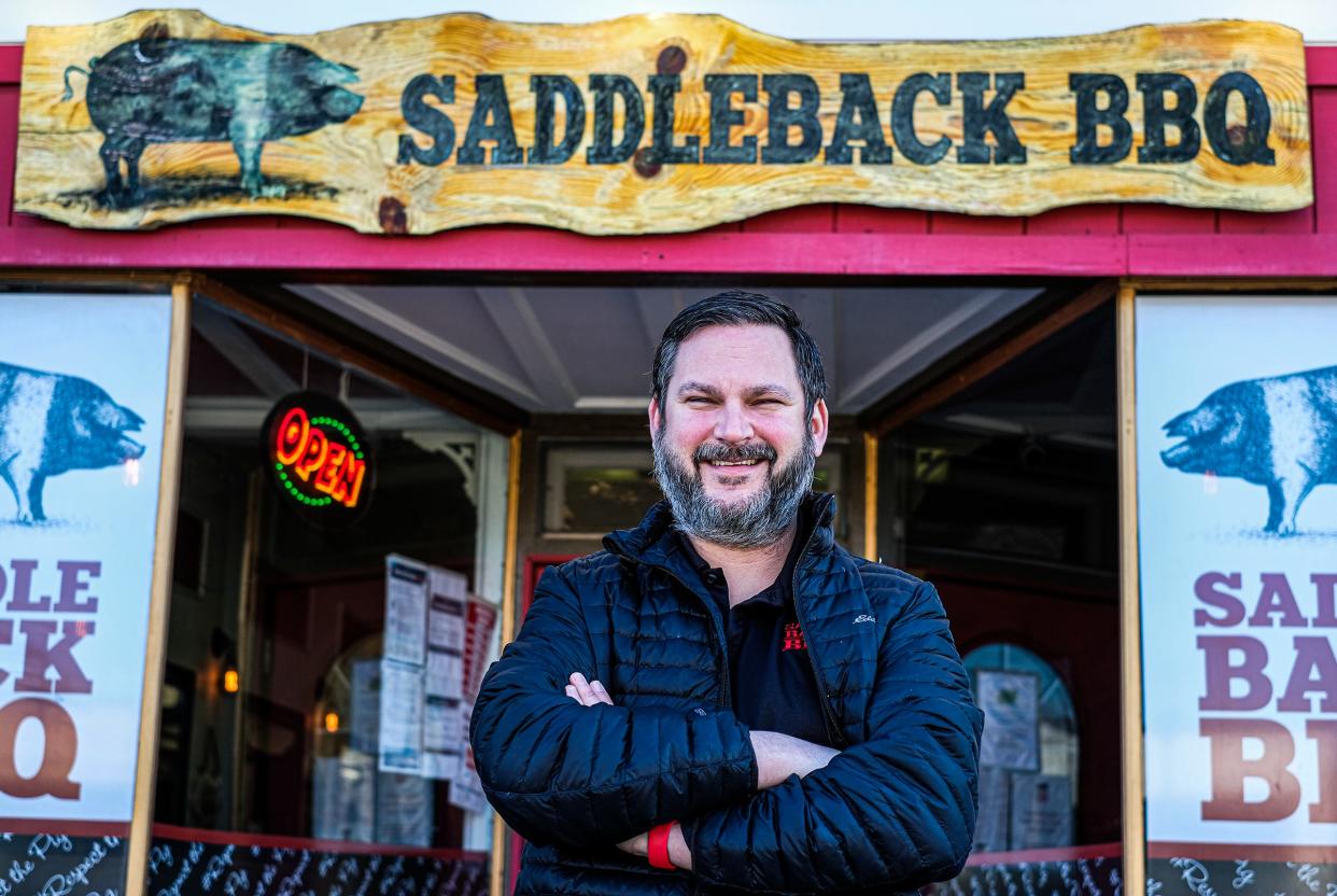 Travis Stoliker, co-owner of Saddleback BBQ, stands in front of his REO Town restaurant Monday, March 29, 2021.