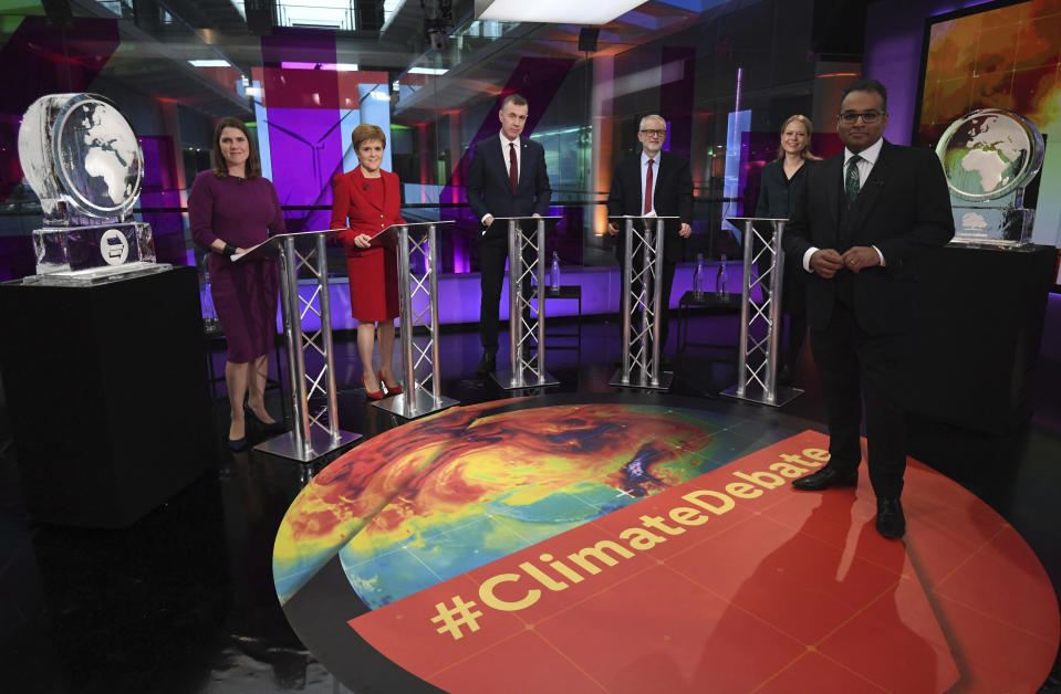 Broadcaster Krishnan Guru-Murthy, foreground, poses for a photo with from rear left, Liberal Democrat leader Jo Swinson, SNP leader Nicola Sturgeon, Plaid Cymru leader Adam Price, Labour Leader Jeremy Corbyn andGreen Party Co-Leader Sian Berry, standing next to ice sculptures representing the Brexit Party and Conservative Party, not appearing at the event, before the start of the Channel 4 News' General Election climate debate at ITN Studios in Holborn, central London, Thursday, Nov. 28, 2019. (Kirsty O'Connor/Pool Photo via AP)