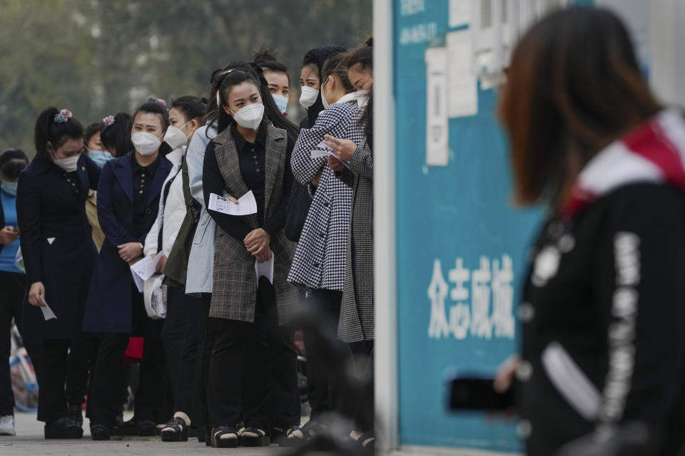 Women wearing face masks wait in line to get their routine COVID-19 throat swab tests at a coronavirus testing site in Beijing, Wednesday, Oct. 26, 2022. The Chinese city of Shanghai started administering an inhalable COVID-19 vaccine on Wednesday in what appears to be a world first. (AP Photo/Andy Wong)