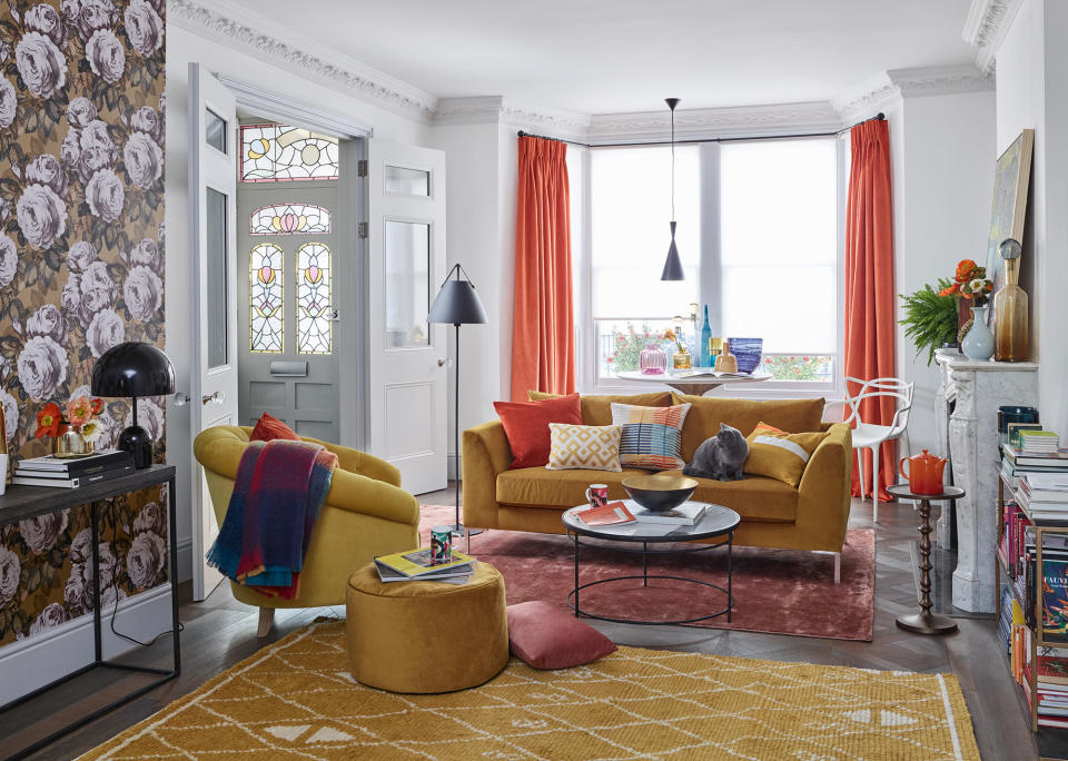 orange curtains in living room with mustard sofas and armchair statement wallpaper and mustard rug