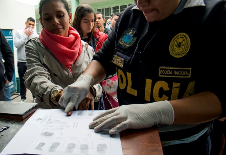 A policeman takes fingerprints of a Venezuelan migrant at an Interpol facility in Lima, Peru