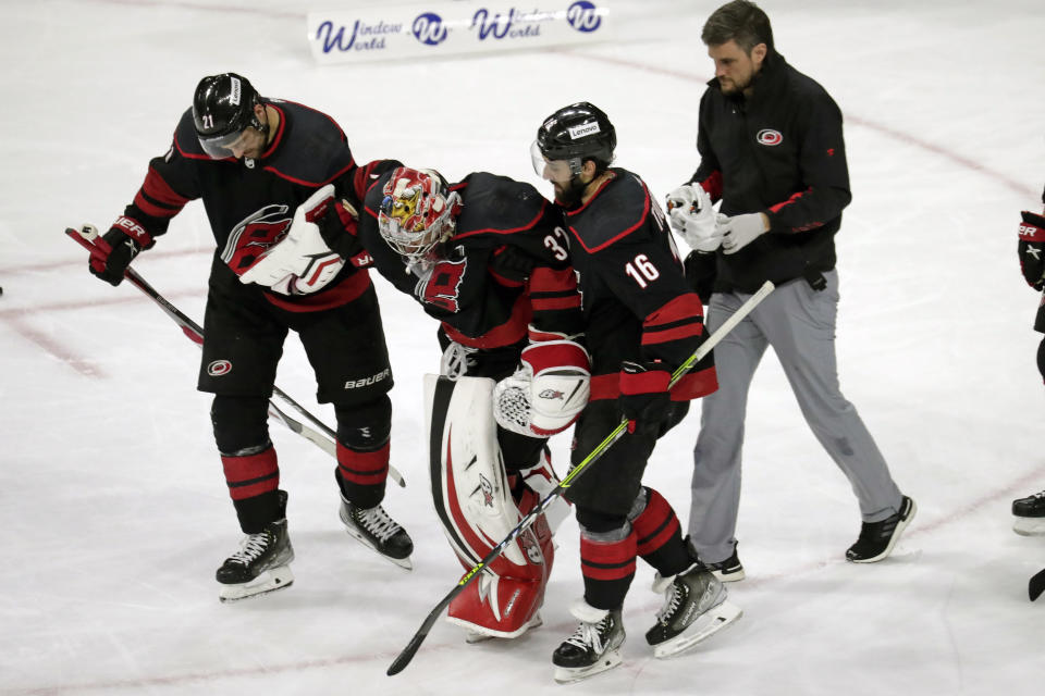 Carolina Hurricanes goaltender Antti Raanta (32) is helped off the ice by right wing Nino Niederreiter (21) and center Vincent Trocheck (16) after he was injured during the second period of Game 7 of an NHL hockey Stanley Cup second-round playoff series against the New York Rangers, Monday, May 30, 2022, in Raleigh, N.C. (AP Photo/Chris Seward)