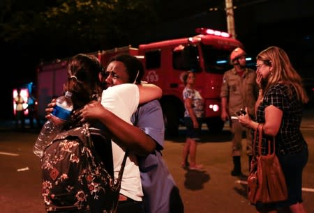 People react after a fire hit the Badim Hospital in Rio de Janeiro