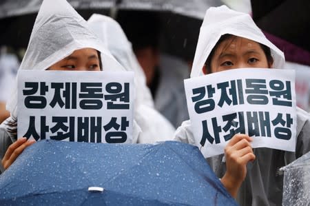 Women hold signs that read "Compensate and apologize for victims of wartime forced labour" during an anti-Japan protest on Liberation Day in Seoul, South Korea