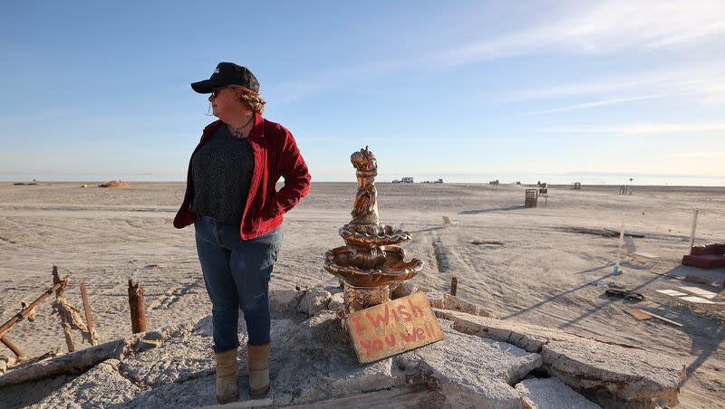 Candace Youngberg stands on the remains of what was once a waterfront pier by the receding shoreline of the Salton Sea in Bombay Beach, Calif., on Friday, Dec. 15, 2023. The water’s edge reached the pictured fountain in 2011.