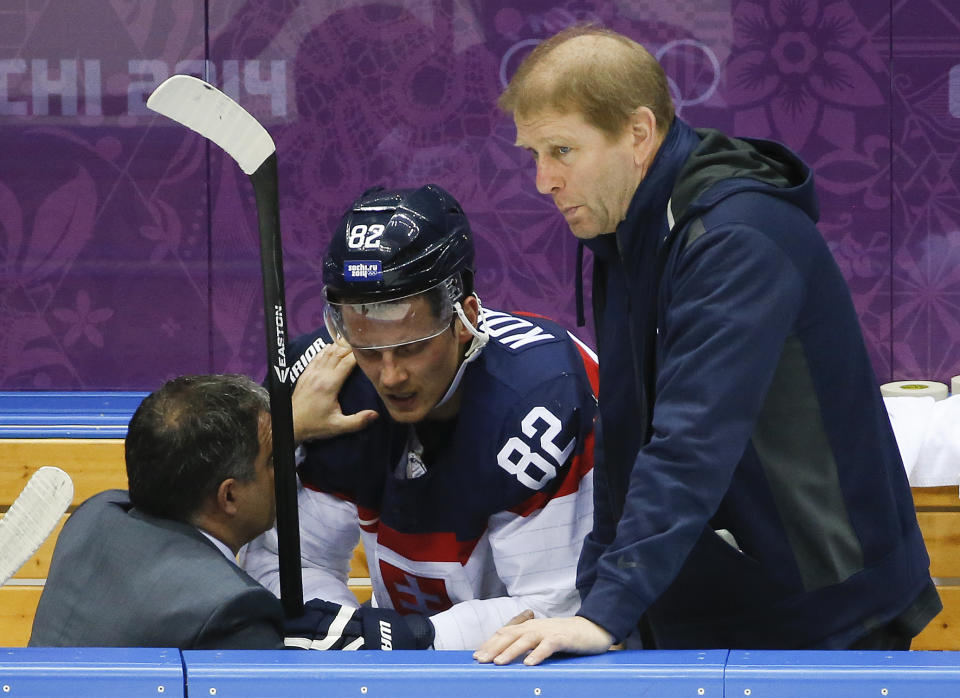 Slovakia forward Tomas Kopecky is checked by a trainer in the first period of a men's ice hockey game against Slovenia at the 2014 Winter Olympics, Saturday, Feb. 15, 2014, in Sochi, Russia. (AP Photo/Mark Humphrey)