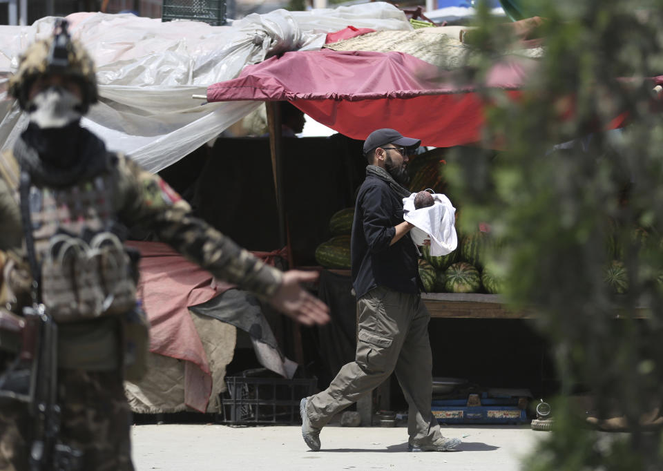 An Afghan security officer carries a baby after gunmen attacked a maternity hospital, in Kabul, Afghanistan, Tuesday, May 12, 2020. Gunmen stormed the hospital in the western part of Kabul on Tuesday, setting off a shootout with the police and killing several people. (AP Photo/Rahmat Gul)