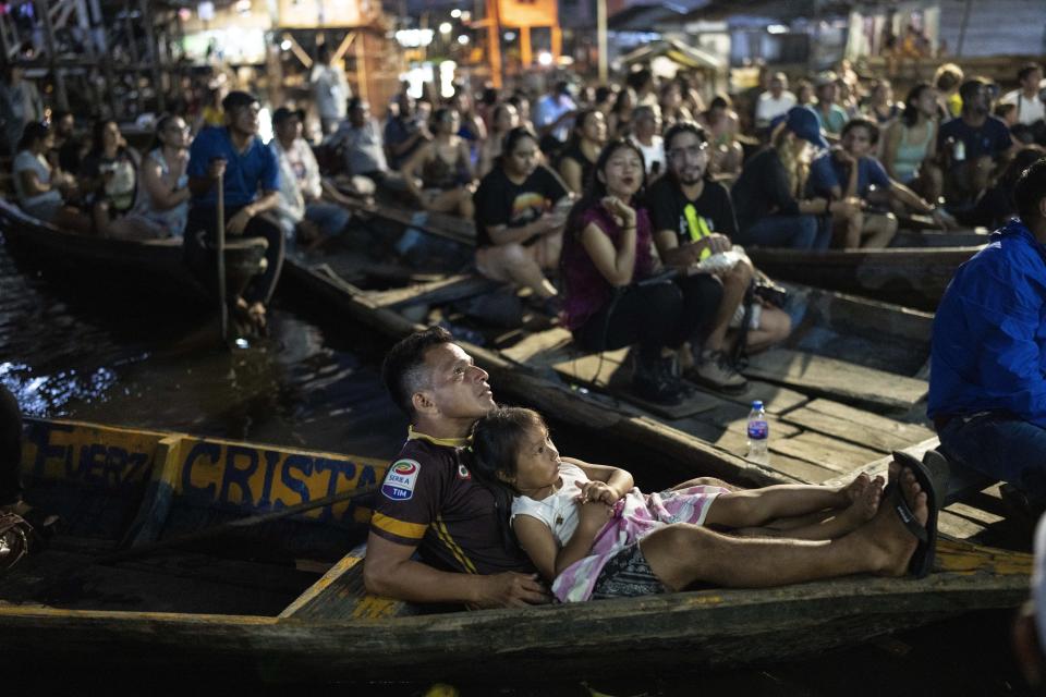 Los espectadores se sientan en botes para ver una película proyectada en una pantalla instalada sobre una estructura de madera durante el Festival de Cine Flotante Muyuna en el barrio Belén de Iquitos, Perú, el sábado 25 de mayo de 2024. (Foto AP/Rodrigo Abd)