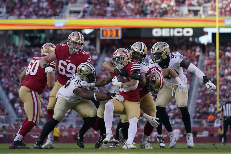 San Francisco 49ers running back Elijah Mitchell, middle, is tackled by New Orleans Saints linebacker Zack Baun, middle right, and defensive tackle David Onyemata, middle left, during the first half of an NFL football game Sunday, Nov. 27, 2022, in Santa Clara, Calif. (AP Photo/Godofredo A. Vásquez)
