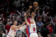 Philadelphia 76ers' Joel Embiid passes the ball away frrom Chicago Bulls' Nikola Vucevic (9) and Alex Caruso (6) during the second half of an NBA basketball game Saturday, Nov. 6, 2021, in Chicago. The 76ers won 114-105. (AP Photo/Charles Rex Arbogast)