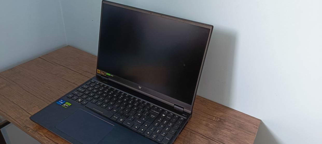  An Abyss Black Acer Predator Helios 16 gaming laptop sitting on a brown wooden desk. 